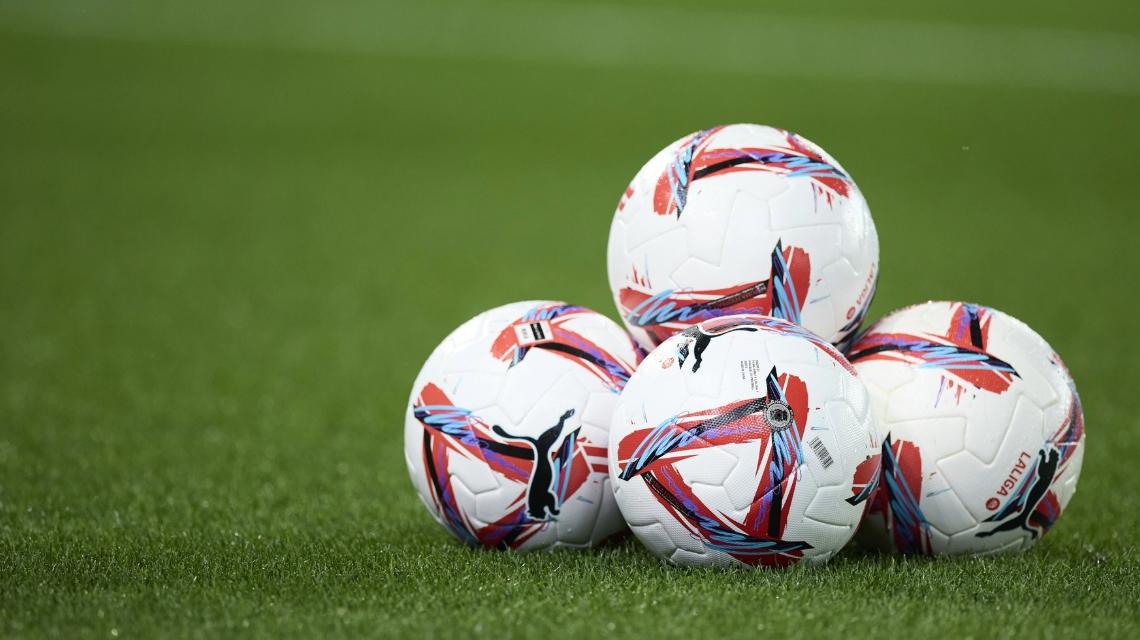 Balones de fútbol agolpados sobre el césped
