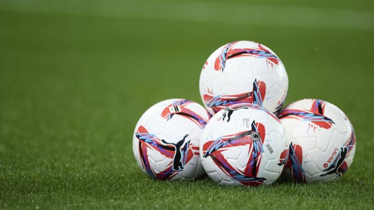 Balones de futbol amuntegats sobre la gespa